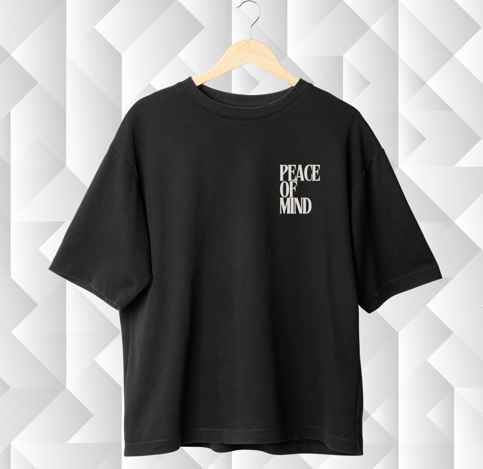 Black t-shirt with 'PEACE OF MIND' text on a geometric patterned wall
